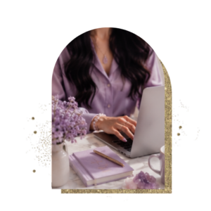 Donna in camicia lilla al computer, con fiori viola, un quaderno e un cristallo di ametista, per il corso Akasha Mastery
